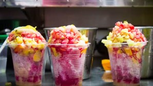 Tre bicchieri di plastica con frutta a strati e una base rosa, probabilmente un dessert.
