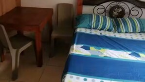 Una camera da letto con un letto, un tavolo in legno, una sedia e una ventola a soffitto.