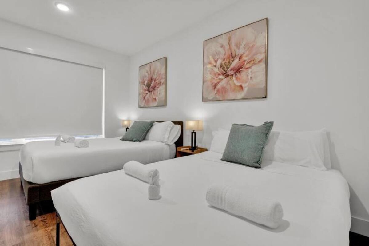 Une chambre d’hôtel avec deux lits, une grande fenêtre et des œuvres d’art accrochées aux murs.
