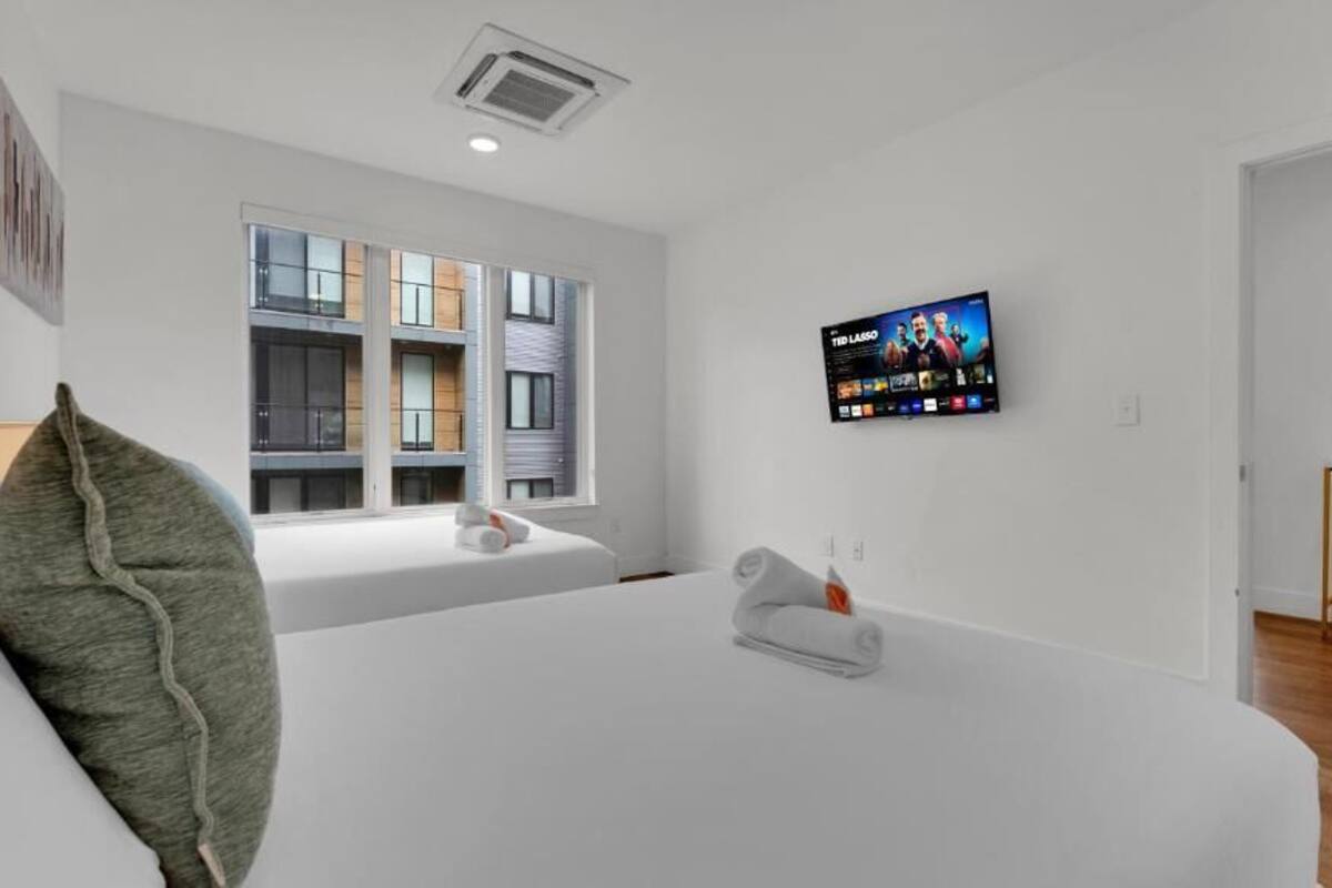 Une chambre d’hôtel moderne dotée d’une grande fenêtre, d’un téléviseur à écran plat et d’un lit parfaitement fait.