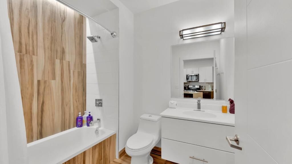 A modern bathroom with a wooden vanity, a toilet, and a mirror above the sink.