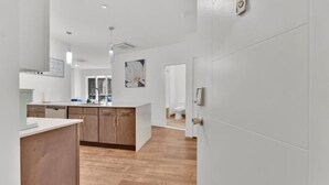 A modern kitchen with wooden cabinets, a central island, and a view into the adjacent bathroom. - Apartmint at Liberty A Philadelphia (Philadelphia)