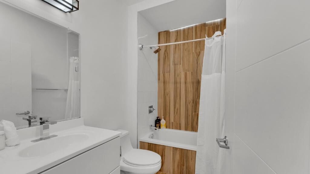 A modern bathroom with a white sink, toilet, and shower area.