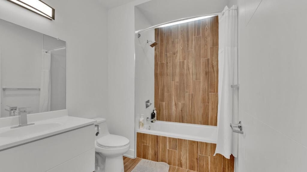 Une salle de bain moderne avec un lavabo, des toilettes et une baignoire, le tout de couleur blanche.