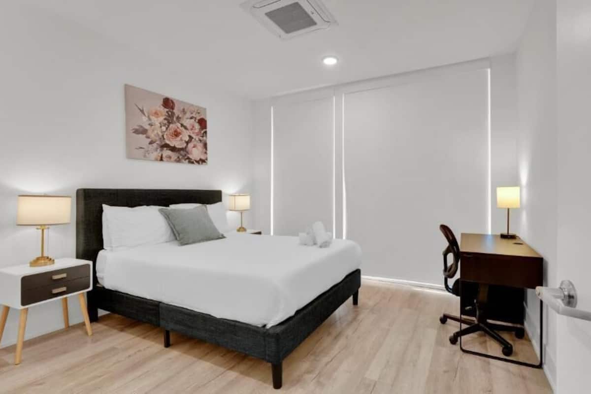 A modern bedroom with a bed, bedside tables, a desk, and a chair.