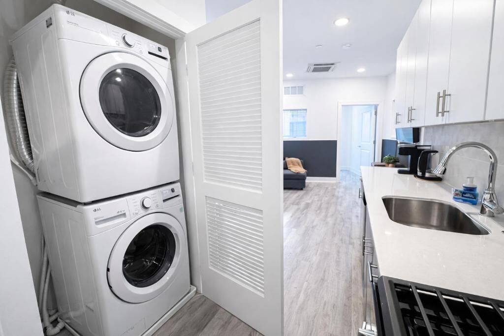A laundry area with stacked washers and dryers, a kitchen with a sink, and a living area with a sofa.