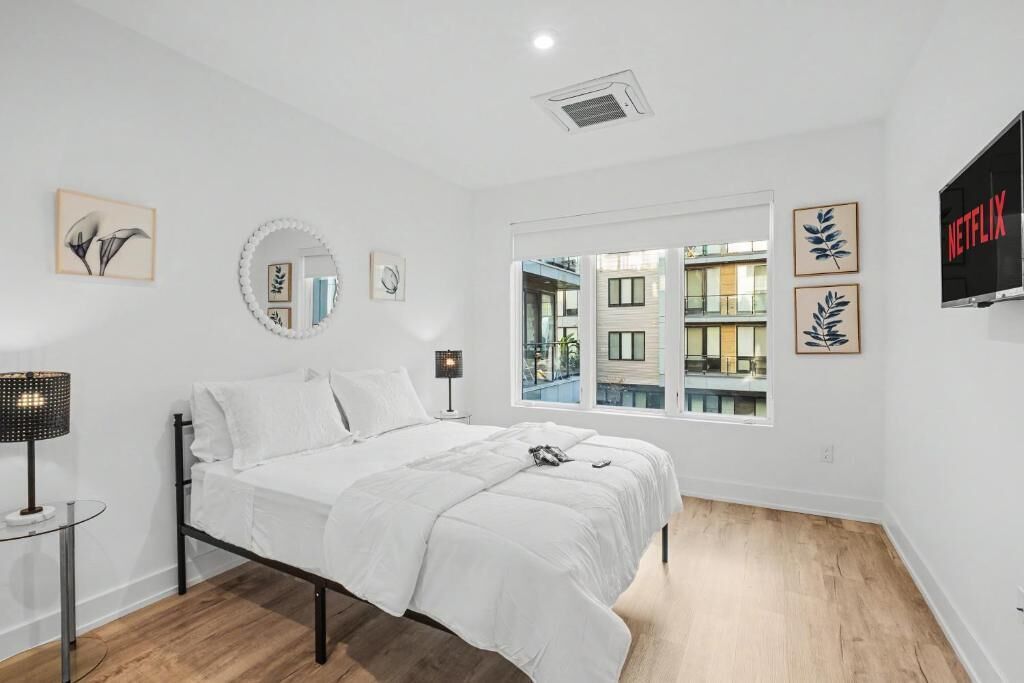Een moderne slaapkamer met een bed, bedlampen, een raam met uitzicht en een tv aan de muur.