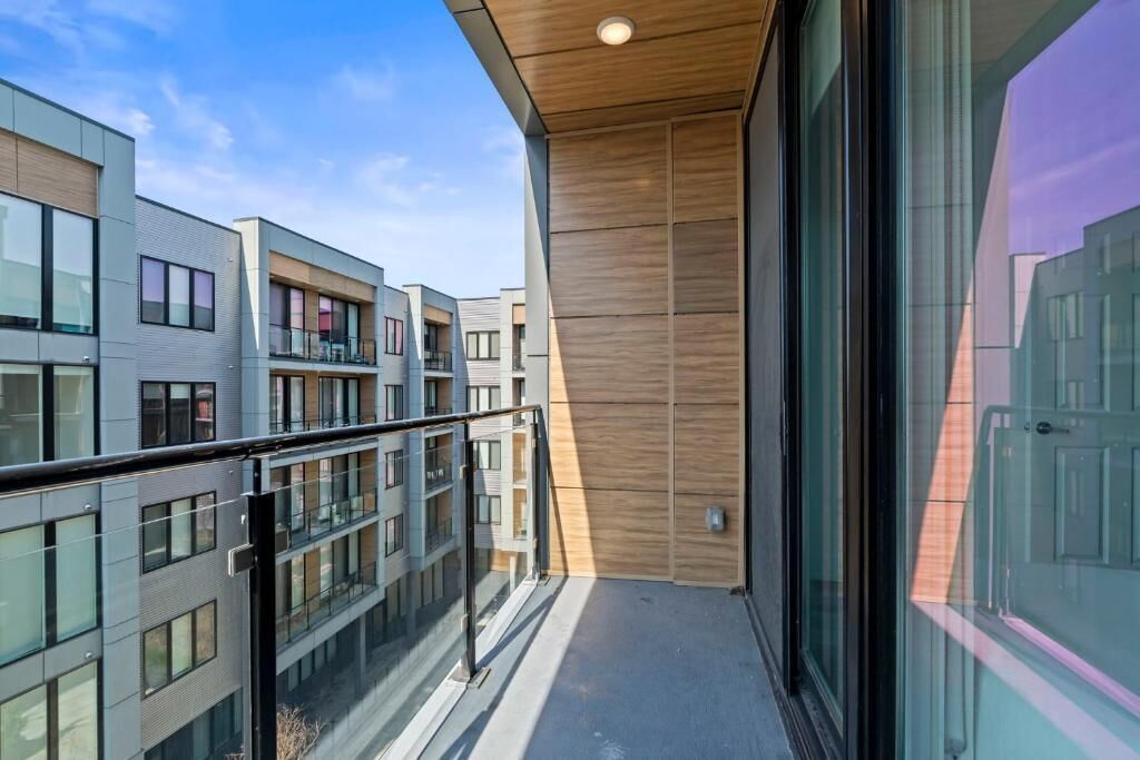 A modern building with a balcony, large windows, and a wooden ceiling.