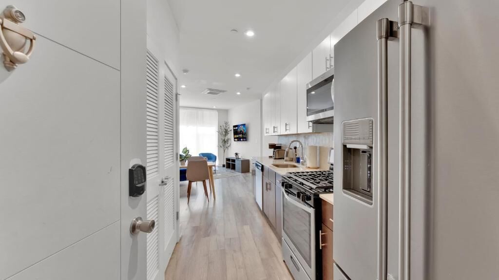 A modern kitchen with a stove, refrigerator, and cabinets.