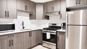 Una cocina moderna con armarios de madera, un refrigerador de acero inoxidable, horno empotrado y microondas.