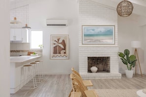 A modern kitchen with white brick walls, a white countertop, and bar stools.
