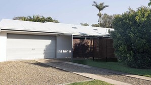 Ein eingeschossiges Gebäude mit Garage, überdachter Auffahrt und gepflegtem Rasen.