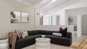 A modern living room with a green sectional sofa, a white coffee table, and a wooden chair.