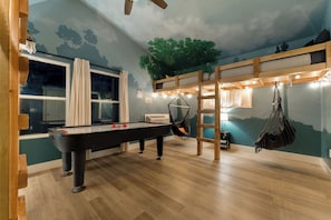 Ein Zimmer mit Billardtisch, Stockbetten und einer Deckenmalerei.