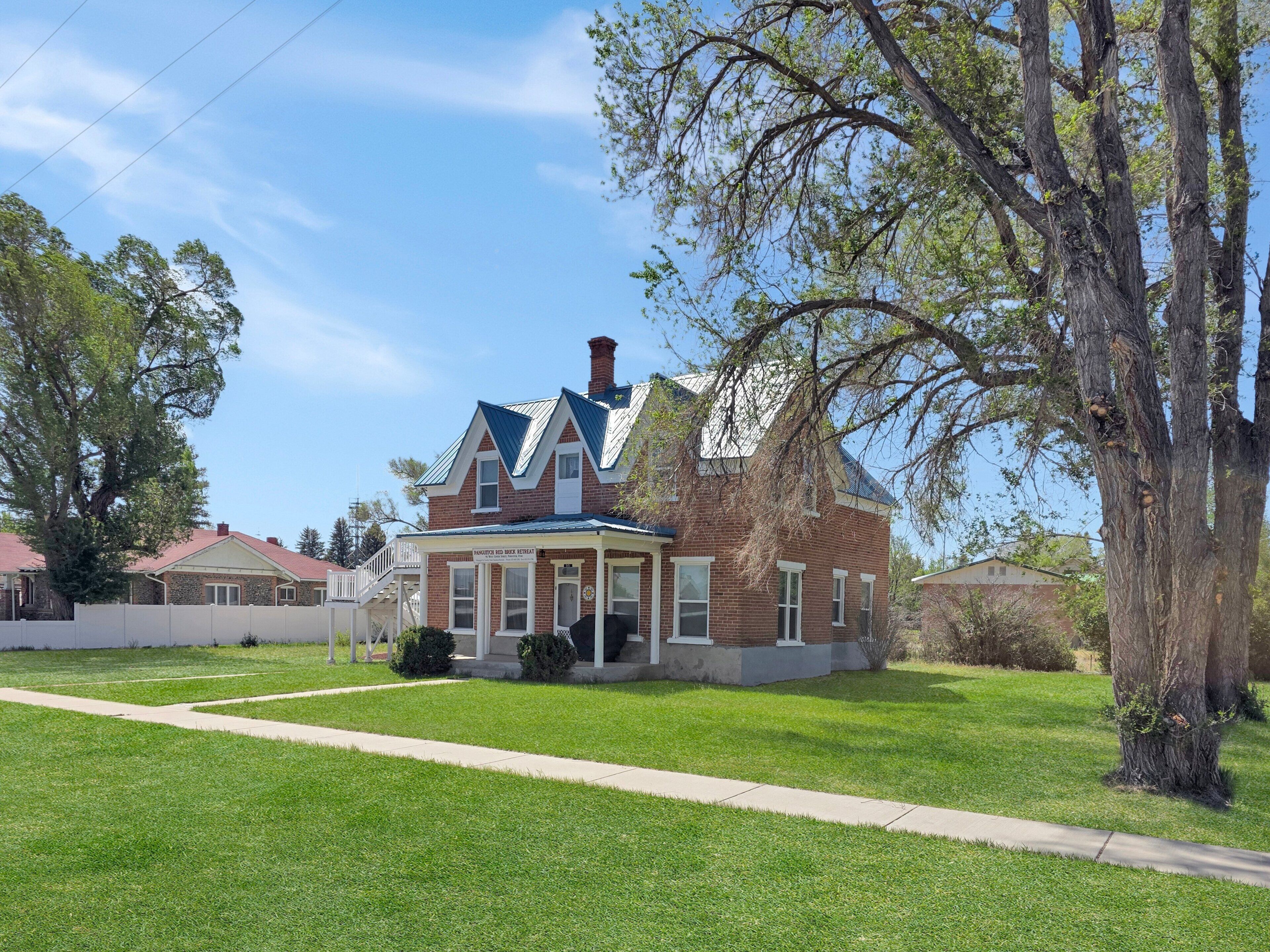 A two-story brick house with a gabled roof, a front porch, and a well-maintained lawn.