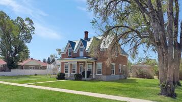 A two-story brick house with a gabled roof, a front porch, and a well-maintained lawn.