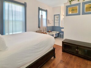 Ein Schlafzimmer mit Bett, einem kleinen Tisch, einem Stuhl, einer Badewanne und einem Schminktisch mit Spiegel.