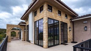 Une maison moderne avec une façade en pierre, de grandes fenêtres en verre et un patio couvert.