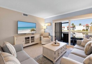 Een woonkamer met een flatscreen televisie, een bank, een bijzettafeltje en een kast.
