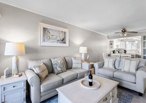 Un salon avec deux canapés, une table basse et un ventilateur de plafond.