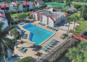 Ein Hotel mit Swimmingpool, Liegestühlen und Palmen.