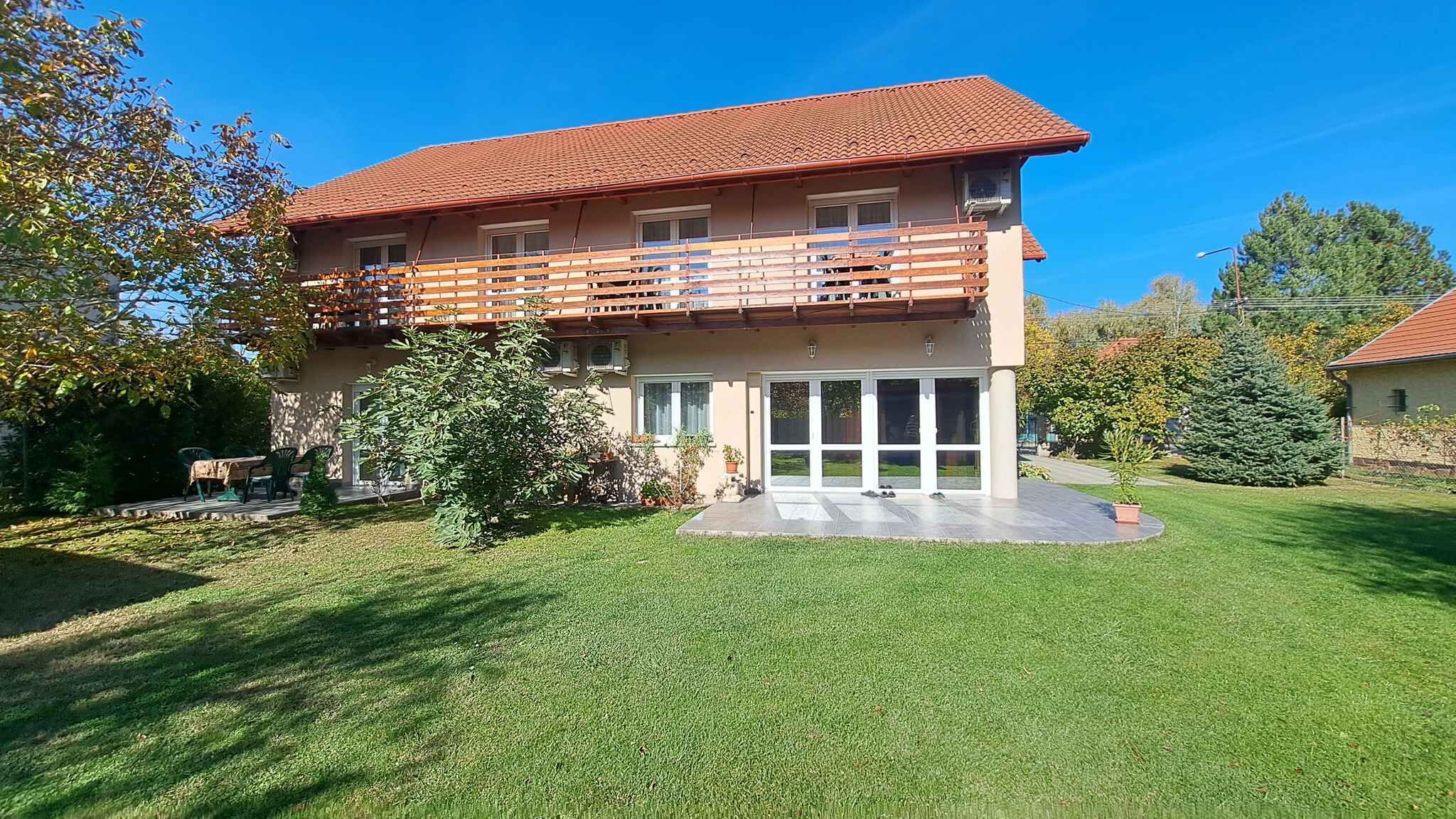 A two-story house with a balcony, a lawn, and a small garden area.
