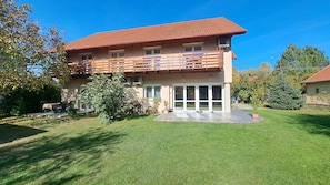 A two-story house with a balcony, a lawn, and a small garden area. - Holiday apartment with Wi-Fi, air conditioning, balcony and parking (Zamárdi)
