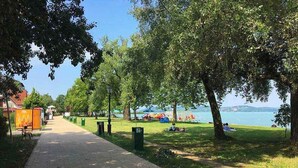 A paved walkway, trees, and a body of water. - Holiday apartment with Wi-Fi, air conditioning, balcony and parking (Zamárdi)
