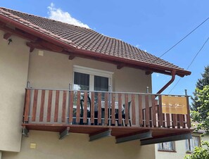 Ein Gebäude mit einem Ziegeldach, einem Balkon mit Holzgeländern und einem Fenster.