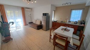 Ein kompakter Wohnraum mit Küchenzeile, Essbereich und einer Couch.