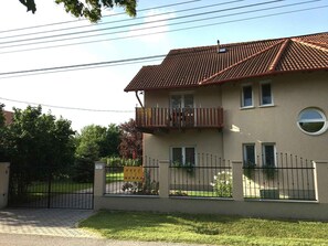A two-story building with a tiled roof, a balcony, and a gated entrance. - Holiday apartment with air conditioning, Wi-Fi, parking and balcony (Zamárdi)