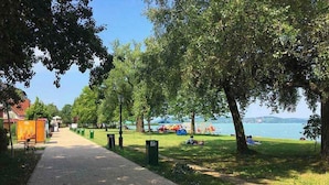 A paved walkway, trees, and a body of water. - Holiday apartment with Wi-Fi, air conditioning, balcony and parking (Zamárdi)