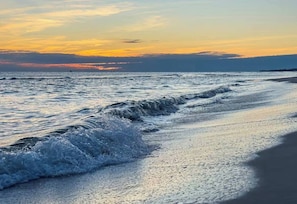 Ein Strand mit Wellen und einem Sonnenuntergang.