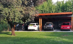 A covered parking area with four cars parked under a roof. - Ground-floor holiday apartment with terrace, Wi-Fi, air conditioning and parking (Zamárdi)