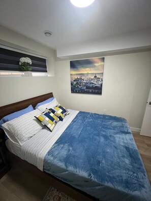 A bedroom with a bed, a window with blinds, a wall-mounted picture, and a ceiling light. - Cozy 2BR Home for 4 | Free Parking | Bus Stop Nearby | Feel at Home in Winnipeg (Winnipeg)