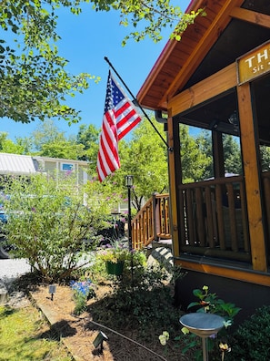 Eine Holzhütte mit Veranda, einer US-amerikanischen Flagge und einem Schild mit der Aufschrift 'The Sit'.