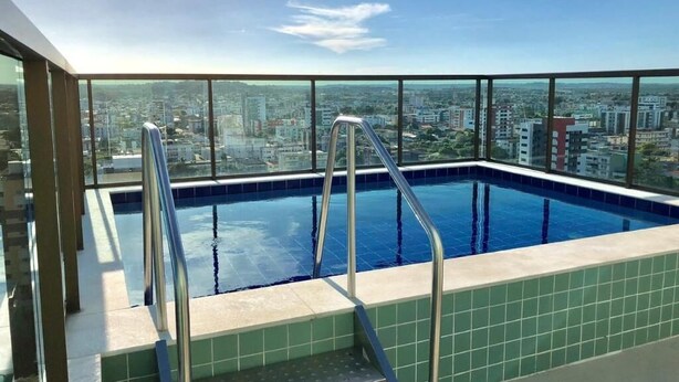 Una piscina al terrat amb baranes de metall i vista a la ciutat.