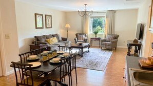 A living room with a sofa, armchairs, a dining table with chairs, a chandelier, and a television. - Convenient & Modern 2 Bed Apt Free Wi-Fi & Parking (Pikeville)