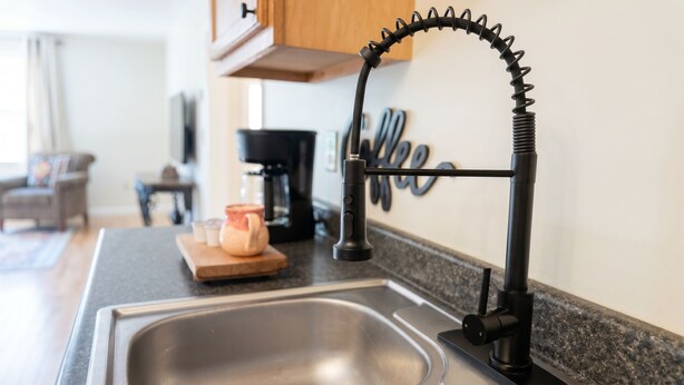 A kitchen with a modern faucet, a coffee maker, and a wooden cutting board with a jar and salt shakers. - Convenient & Modern 2 Bed Apt Free Wi-Fi & Parking (Pikeville)