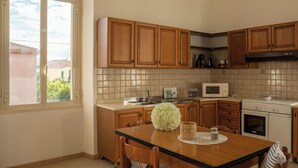 Una cocina con armarios de madera, salpicadero de azulejos, una mesa de comedor con sillas, un microondas y un horno.