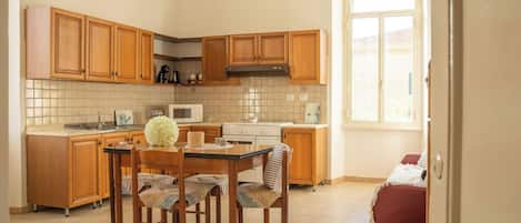 A kitchen with wooden cabinets, a tiled backsplash, a central island with chairs, a stove, and a window.