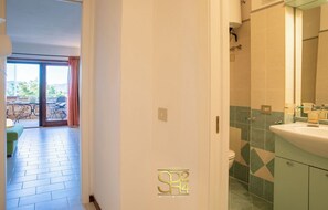 A hotel room with a bathroom, a dining area with a table and chairs, and a view of the outdoors. - The Port of Dreams - Porto Rotondo (Porto Rotondo)