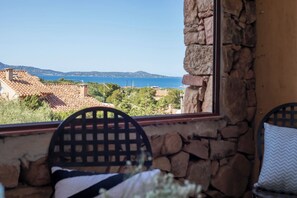A stone wall, a window with a view of the sea, and a chair with a cushion. - The Port of Dreams - Porto Rotondo (Porto Rotondo)