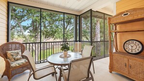 A covered patio with wicker furniture, a round table, and a clock on a wooden cabinet. - Family-Friendly Retreat Near Disney (Davenport)