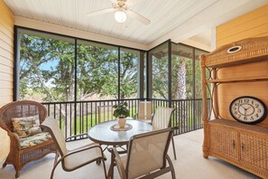 A covered patio with wicker furniture, a round table, and a clock on a wooden cabinet. - Family-Friendly Retreat Near Disney (Davenport)