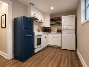 A compact kitchen with a blue refrigerator, white cabinets, a microwave, an oven, and a white washing machine. - Arlington Rentals Unit 3b (Studio) (Jefferson)