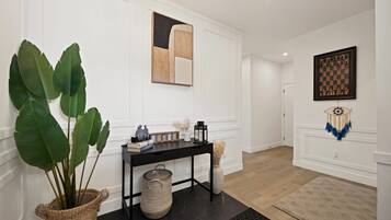 Un pasillo con una planta en maceta, una mesa negra con objetos decorativos, un tablero de ajedrez y un atrapasueños.