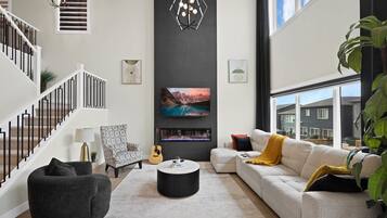 Una sala de estar moderna con una escalera, una chimenea, un sofá y un ventanal grande.