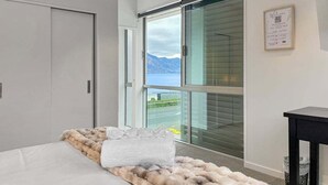 Ein modernes Schlafzimmer mit großem Fenster, einem Bett mit Felldecke und Blick ins Freie.