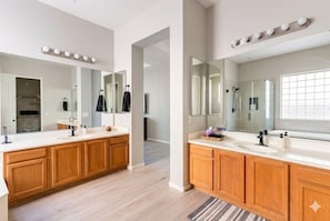 Une salle de bain moderne avec des meubles en bois, un grand miroir et un meuble-lavabo.